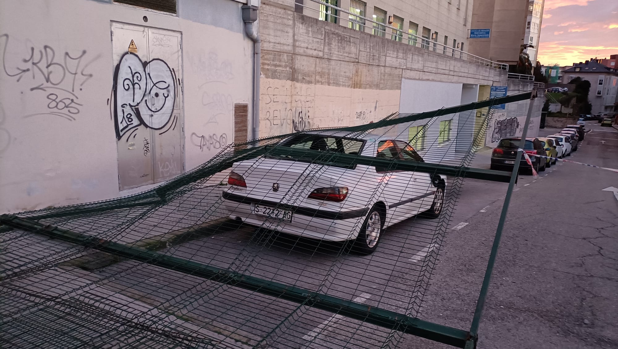 Valla del colegio San Martín de Santander que ha caído sobre algunos coches.