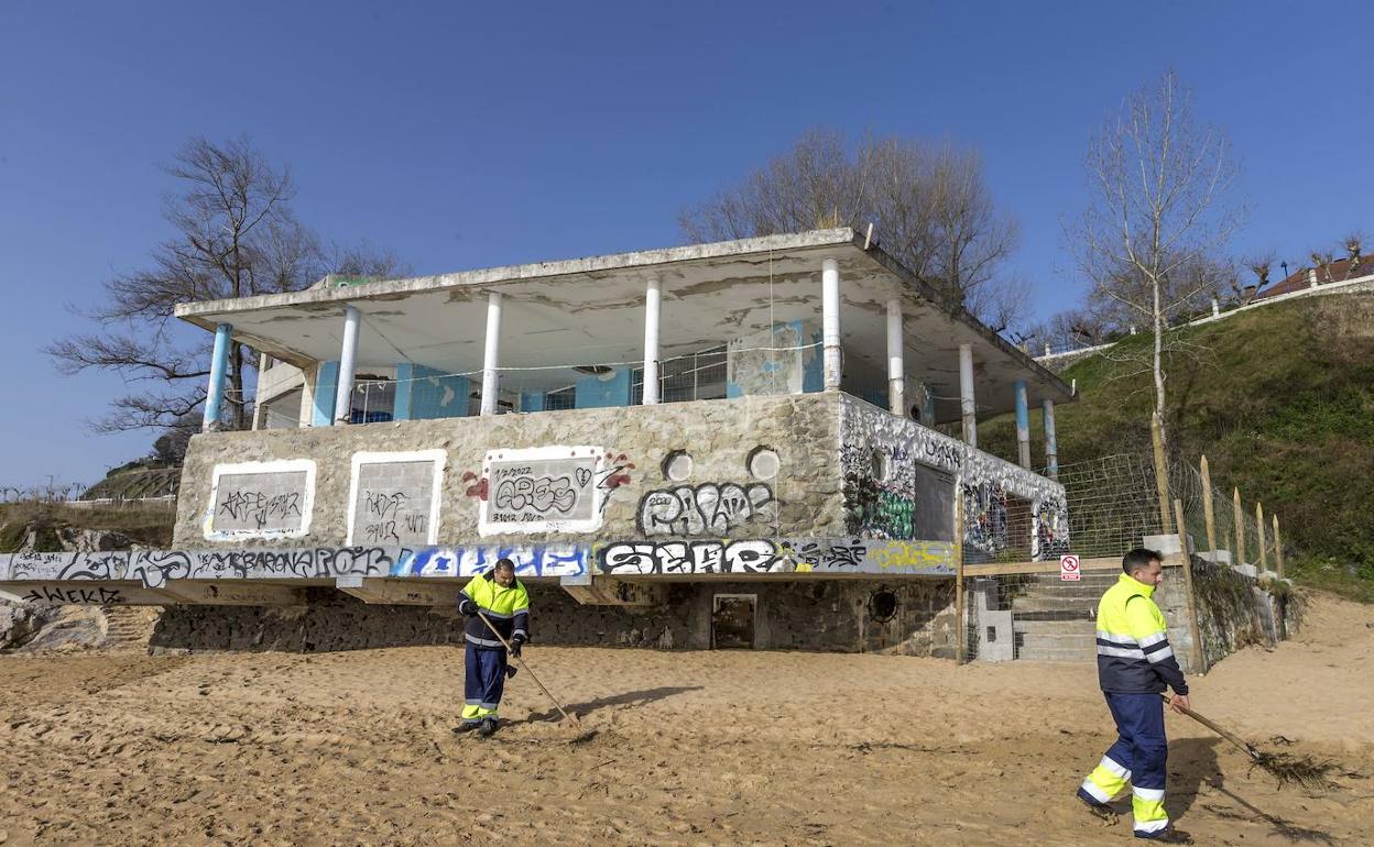 Dos operarios limpian la playa de La Magdalena, frente al Balneario de La Horadada. 