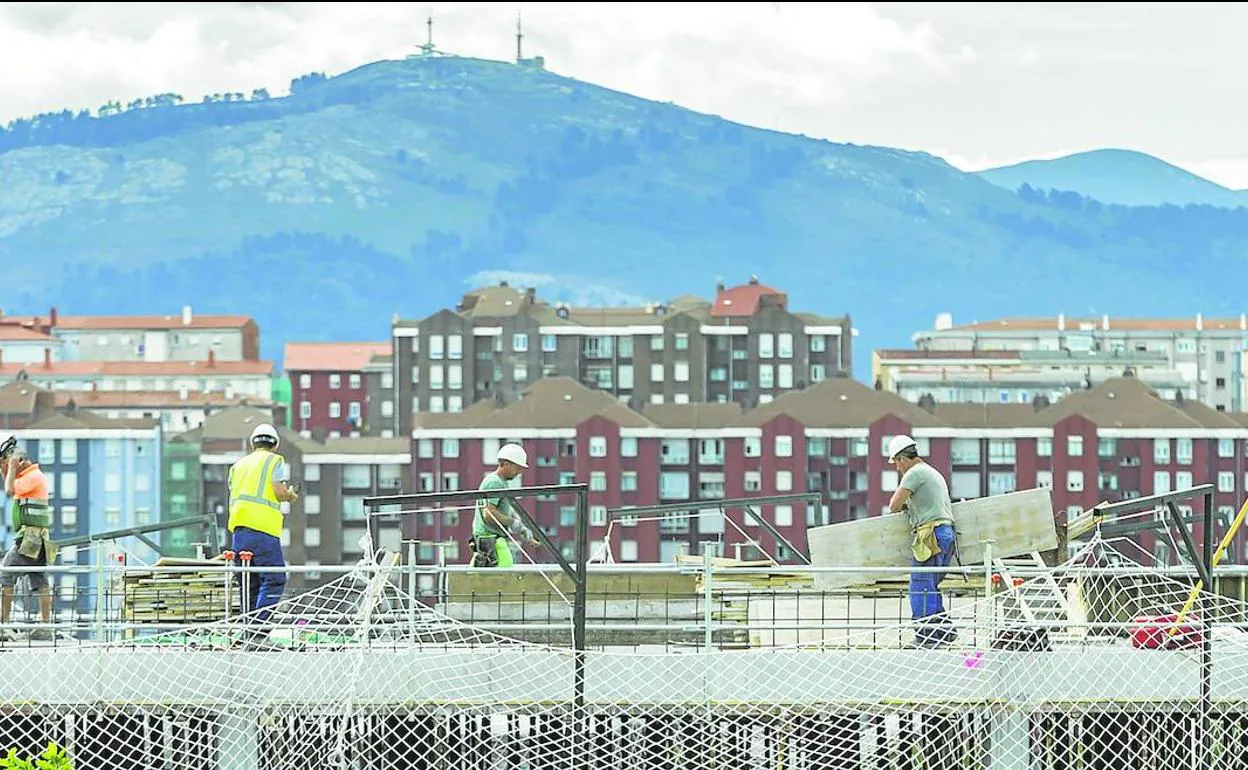 Unos albañiles se afanan en preparar el tejado de un edificio de reciente construcción en Cantabria.