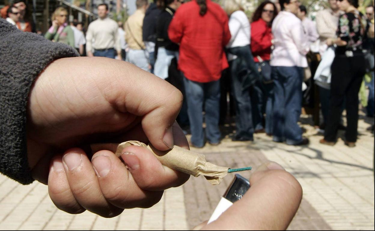 Un joven enciende un petardo en una celebración.