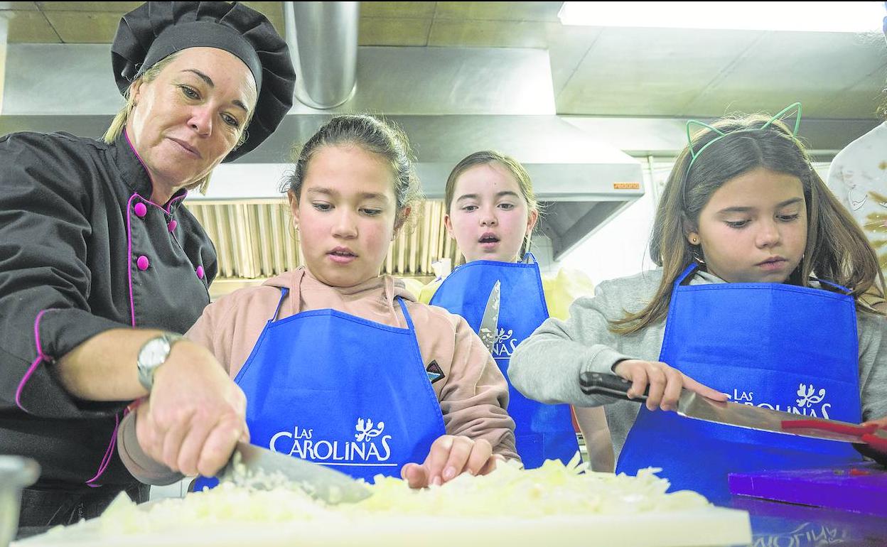 Yolanda López Hoyos, docente de cocina y turismo, explica a Amelia, Elia y Lucía, como coger el cuchillo para picar la cebolla. 