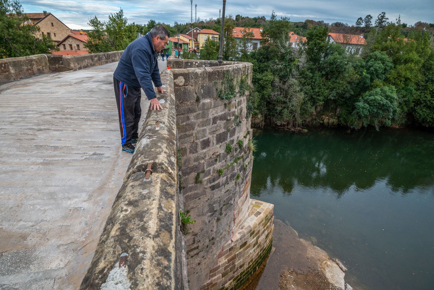 Un vecino observa el río y el estrado de los pilares del puente tras su reforma el día de su reapertura, que causó gran expectación en los municipios de la zona.