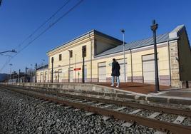 Un vecino aguarda la llegada del tren, ayer, en la estación de Sierrapando, frente al edificio abandonado que sigue pendiente del plan