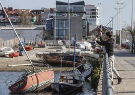 Un chico pesca junto a varios barcos abandonados en el barrio Pesquero.