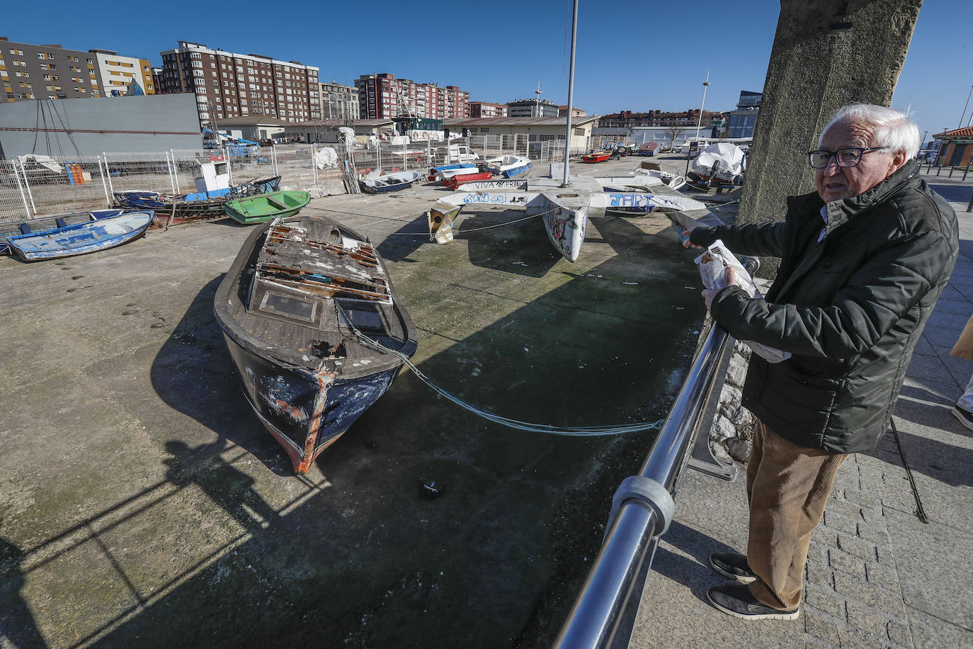 Un hombre señala los barcos acumulados en la rampa, que llevan años abandonados y cada vez en peor estado.