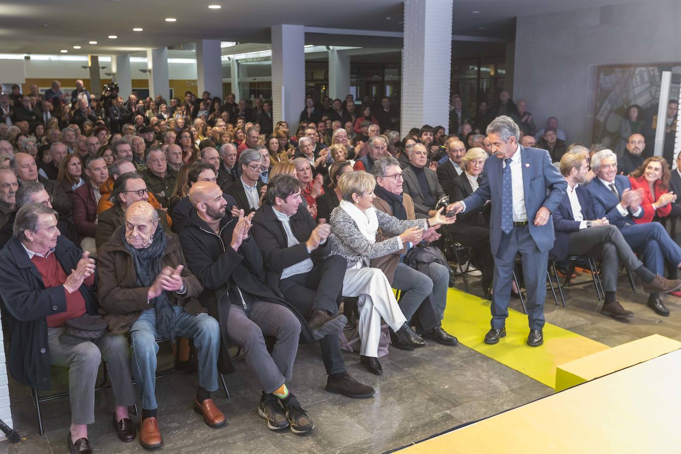 Miguel Ángel Revilla entrega el móvil a su mujer Aurora Díaz ante la atenta mirada del diputado del PP Lorenzo Vidal de la Peña, cuya presencia sorprendió en el acto del PRC.