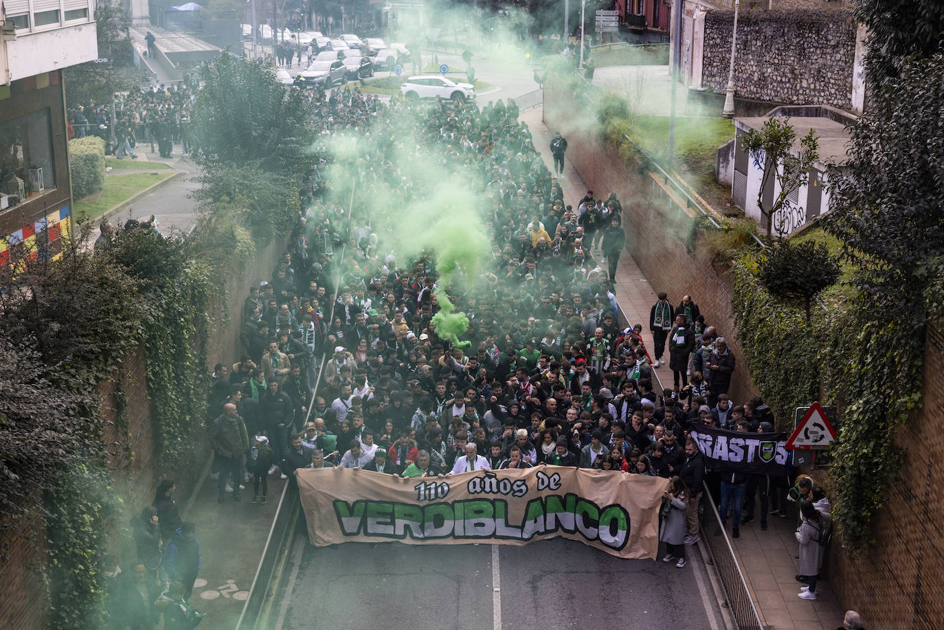 Una marea de aficionados que se dispone a entrar en el túnel de Tetuán se vislumbra entre el humo verde de una bengala.