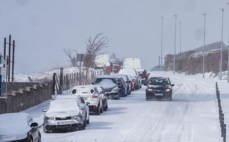 Imagen principal - 1. Las carreteras de Campoo se tiñeron de blanco. | 2. Una mujer se protege del intenso viento y la nieve en Reinosa. | 3. Operarios limpian las aceras de nieve para facilitar el tránsito de los ciudadanos.