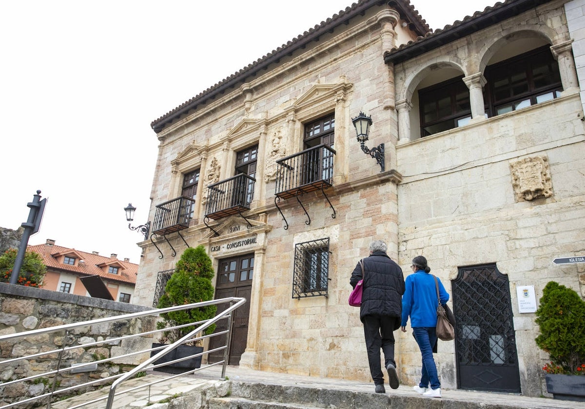 Dos mujeres acceden al Ayuntamiento, sin banderas en la fachada.