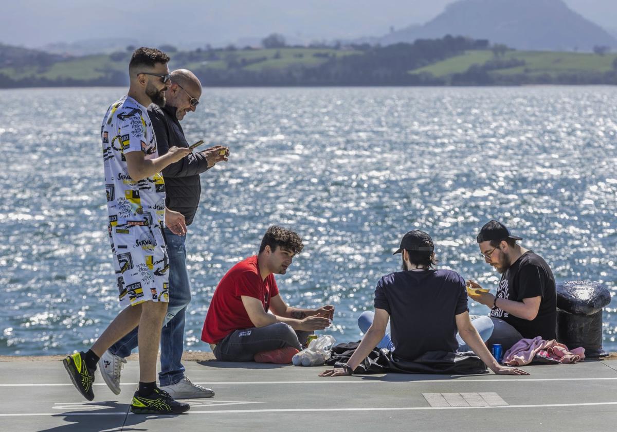 Un grupo de jóvenes aprovecha el buen tiempo para almorzar con vistas a la bahía, junto al Centro Botín.