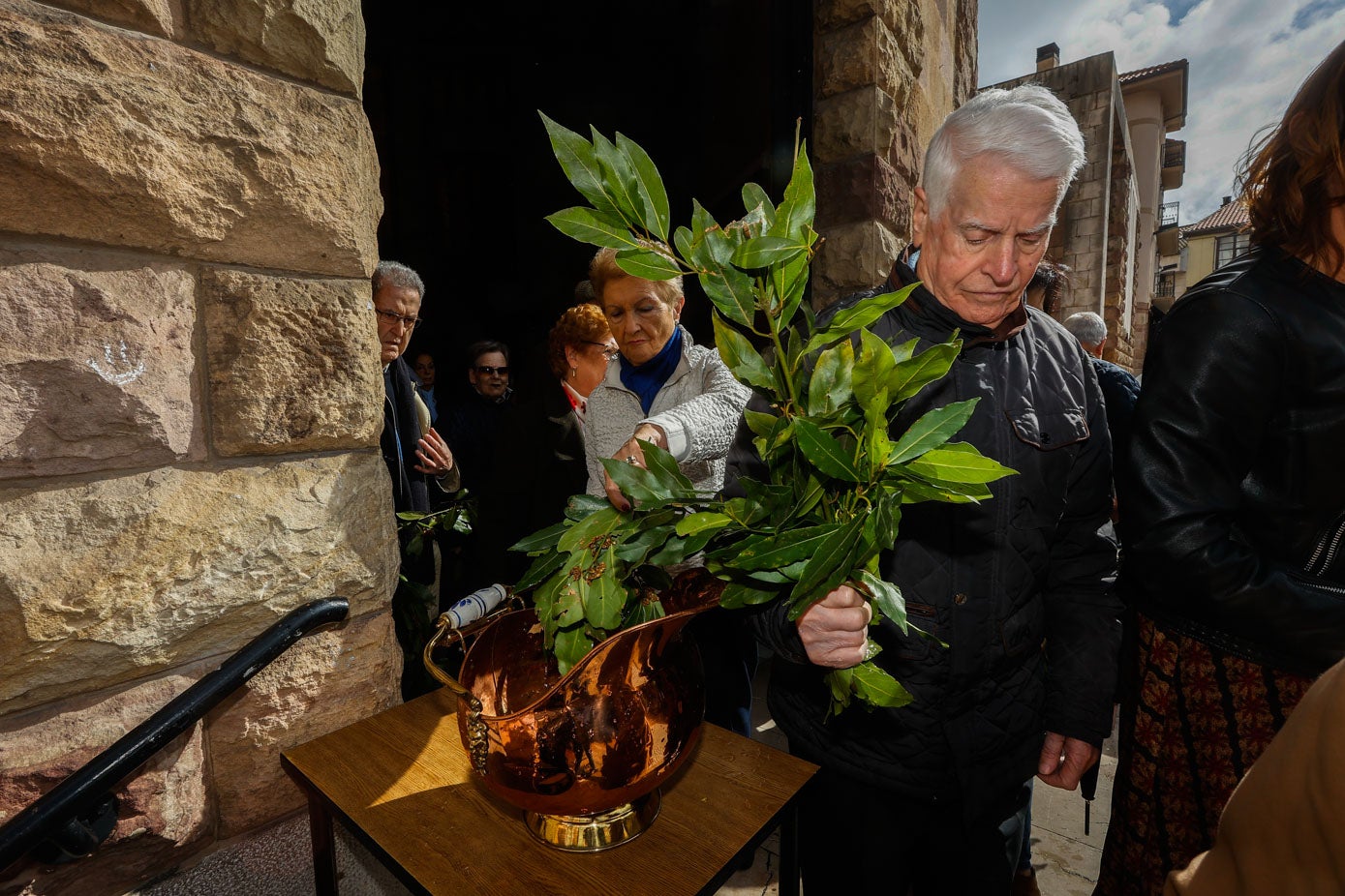 Los propios fieles han bañado sus ramas de laurel en agua bendita a la salida del templo.