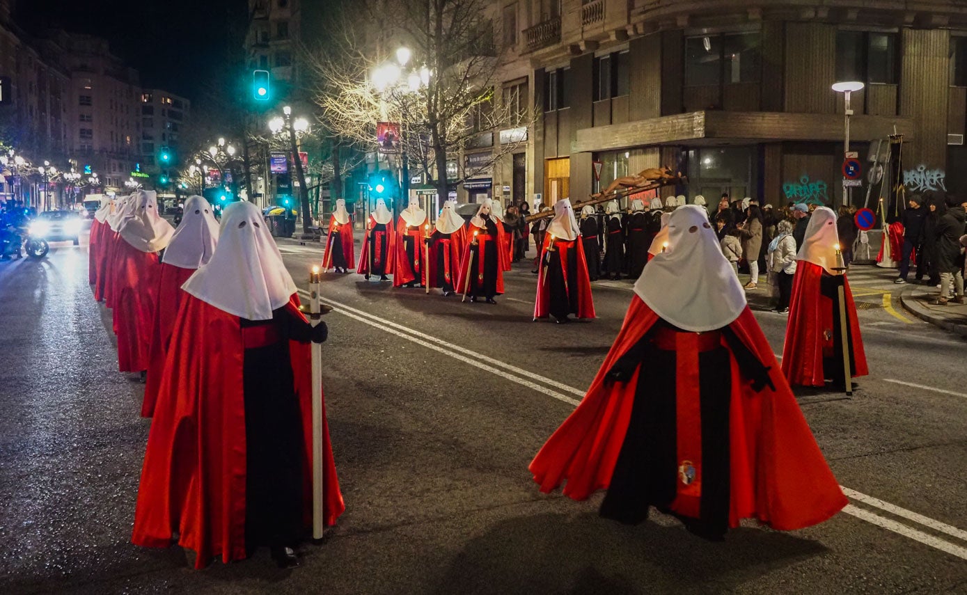 La vestimenta de los nazarenos consta de túnica y zapato negro, capa y fajín rojos y cubrerrostro blanco. Escudo coronado por la realeza de San Fernando, en la mitad izquierda aparecen las armas de Castilla y León y en la derecha las de la Ciudad de Santander.