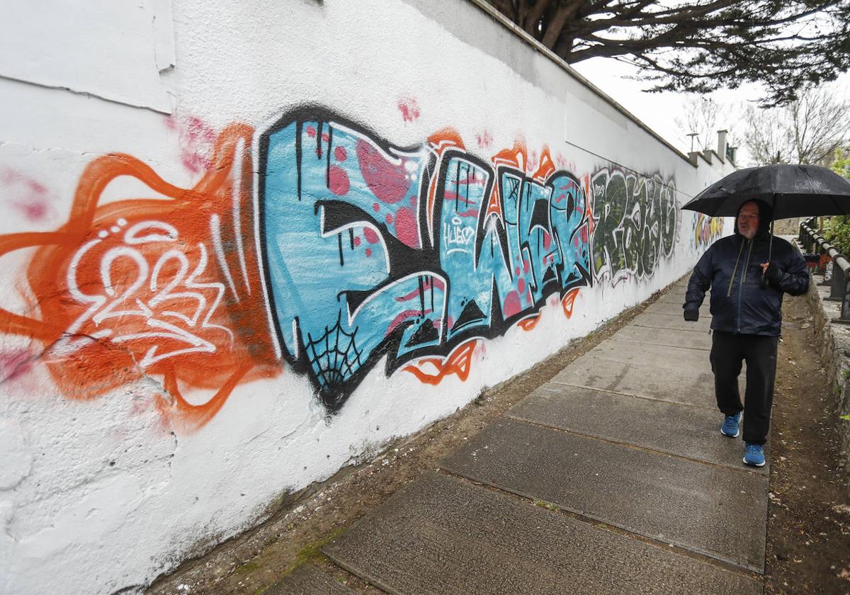 Ciudadano paseando por la senda de Mataleñas, a su paso por zona afectada de nuevo por los grafitis.