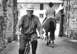 Fede, que va sobre bicicleta, se cruza con otro vecino que va montado a caballo en el acceso a la Plaza de los Cañones