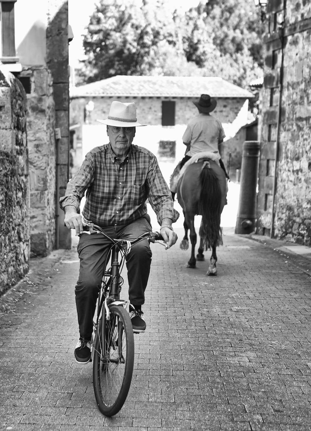 Fede, que va sobre la bicicleta, se cruza con otro vecino que va montado a caballo en el acceso a la Plaza de los Cañones.