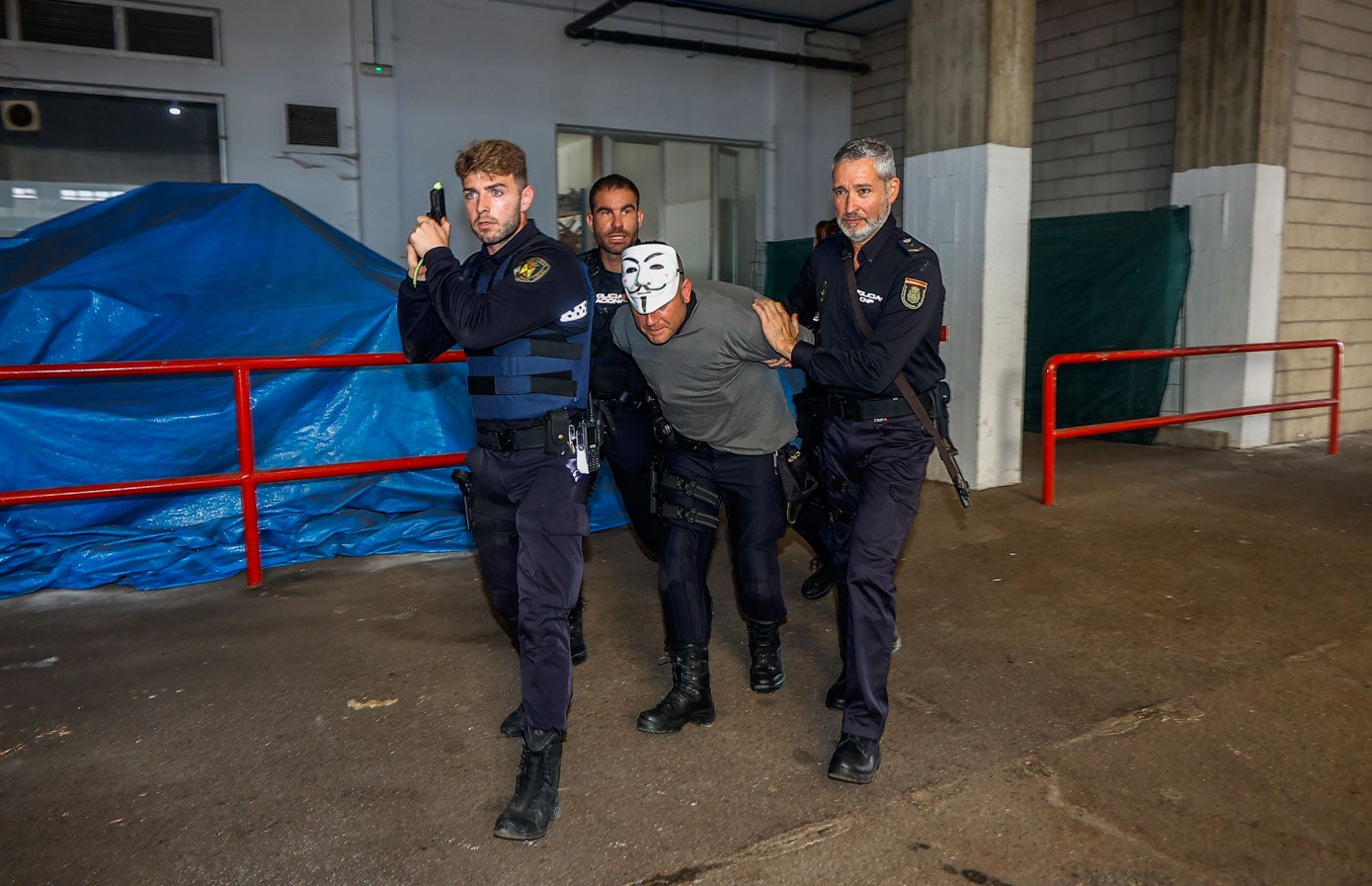 Uno de los falsos terroristas, enmascarado, es reducido por los policías. 