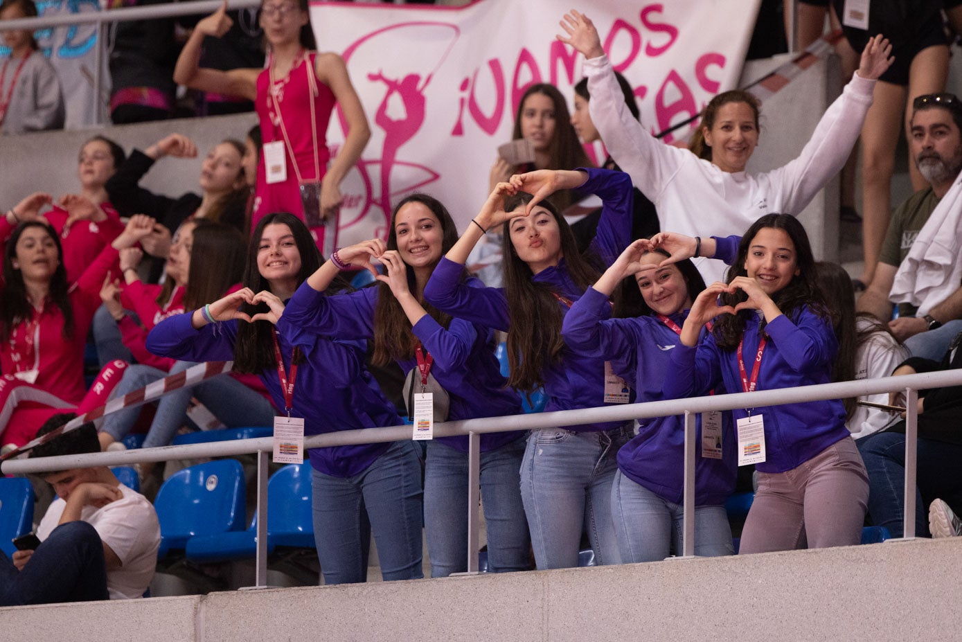 Cinco gimnastas dibujan un corazón con sus manos en la grada.