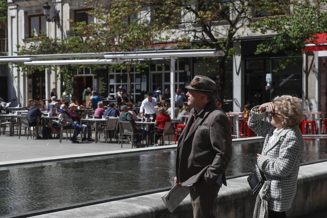 Otra pareja disfruta del buen tiempo que hubo esta mañana en Santander. Al fondo, una terraza llena de clientes. 