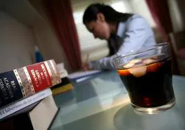 Una joven estudia junto a un vaso de refresco.