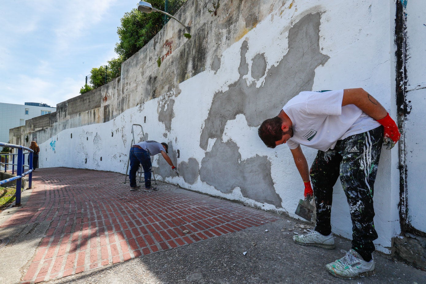 Néstor del Barrio limpia, junto a otro compañero, el muro.