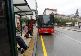 Usuarios del Torrebús aguardan a la llegada de un autocar, en la calle Julián Ceballos de Torrelavega.