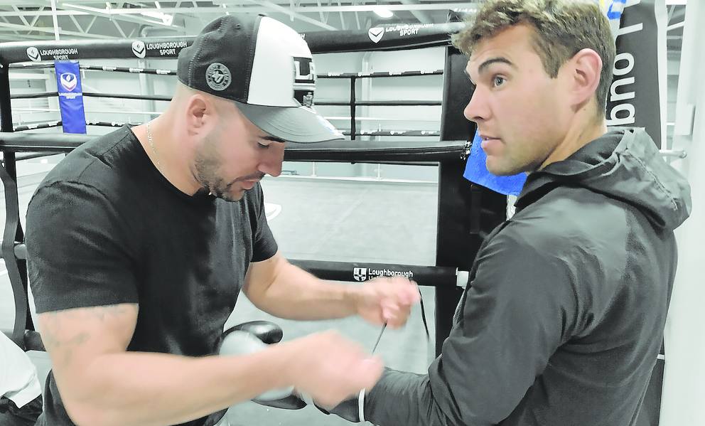 Ángel Fernández, entrenador de 'El Niño', ayuda al púgil torrelaveguense a ponerse los guantes antes de comenzar su rutina de entrenamiento matinal.