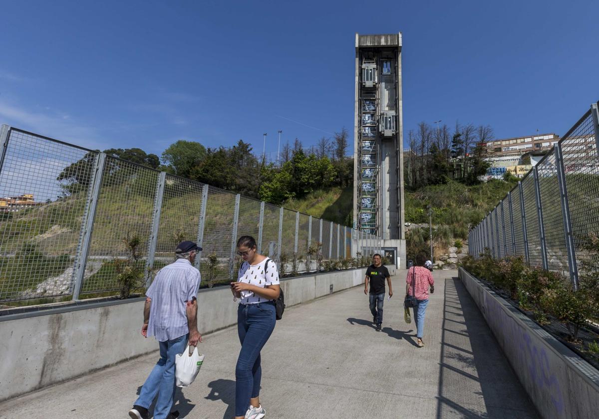 Usuarios del ascensor que une la calle Alta con Castilla-Hermida, ayer, atraviesan la pasarela que lleva a la instalación que está averiada.