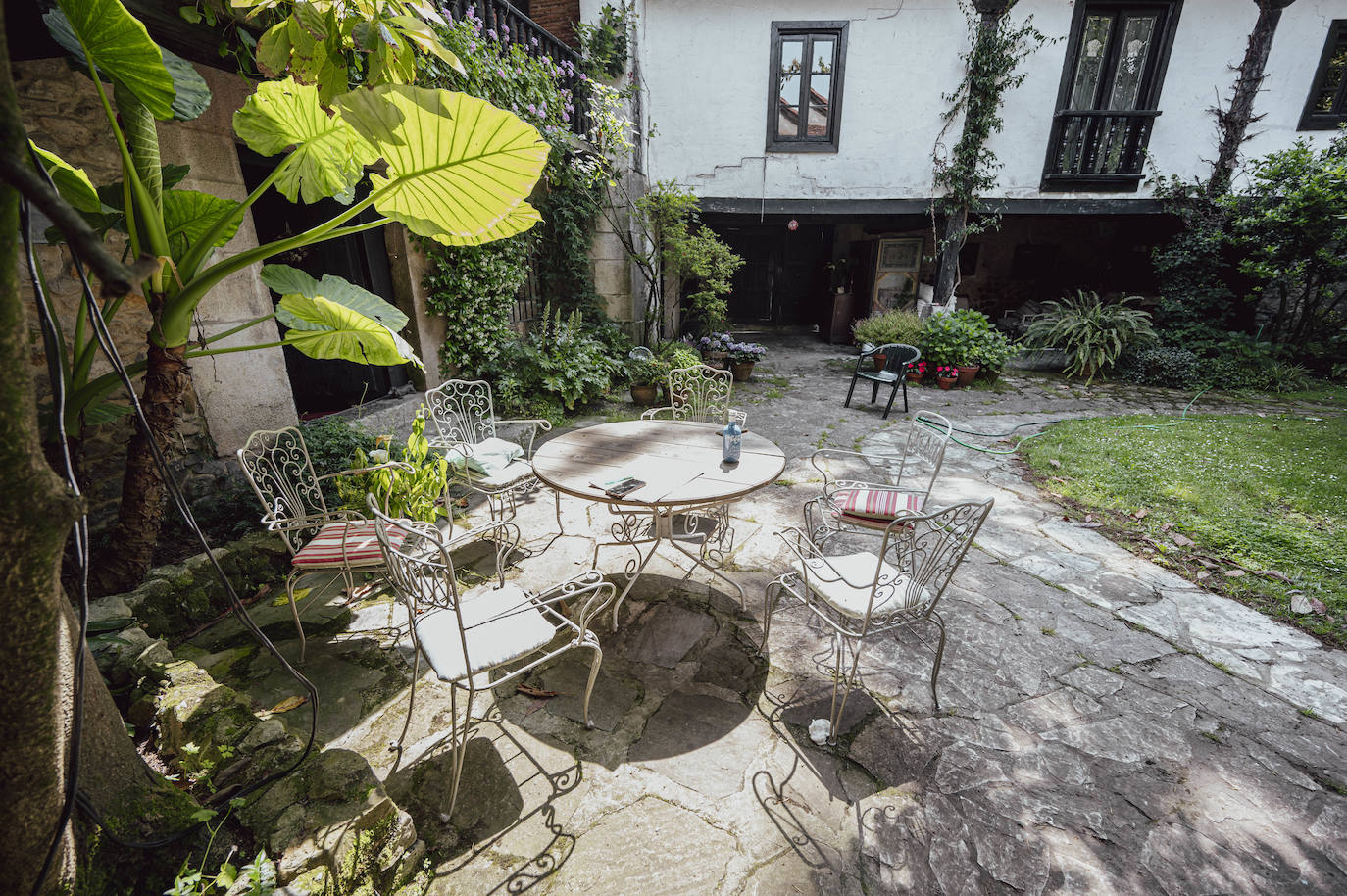 Un rincón del patio, con mesa y sillas de hierro.