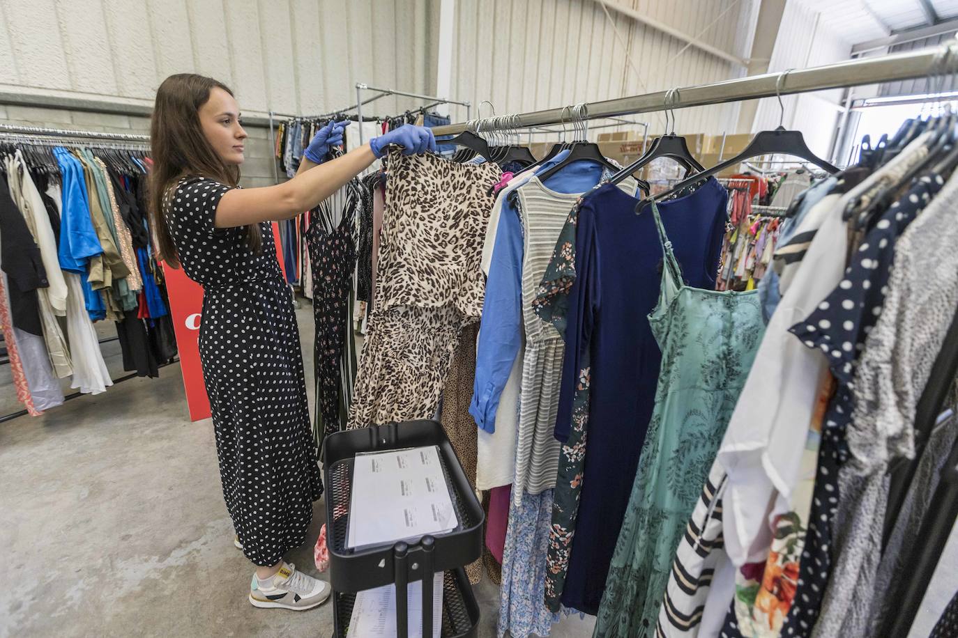 Una de las trabajadoras de la entidad ordena los vestidos.