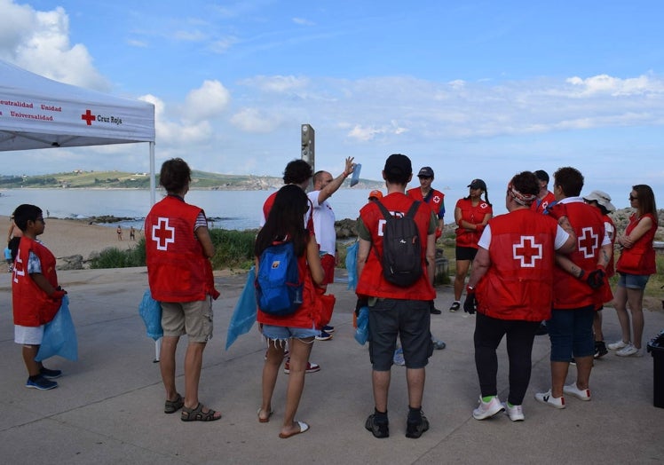 Imagen principal - Arriba los voluntarios escuchan al coordinador de Cruz Roja y técnico ambiental Javier Cacho, al que se le puede ver debajo portando una bolsa de basura, y sobre estas líneas un voluntario en acción detectando residuos. 