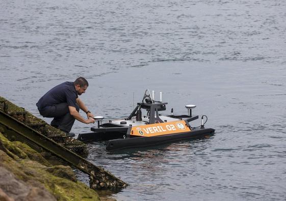 Un profesional de la Armada coloca el dron marino en la superficie del agua, en la ría San Martín.