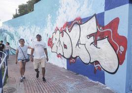 Varios vecinos paseando este domingo junto al mural artístico de la senda de Mataleñas en el que ha aparecido un grafiti el pasado viernes por la noche.