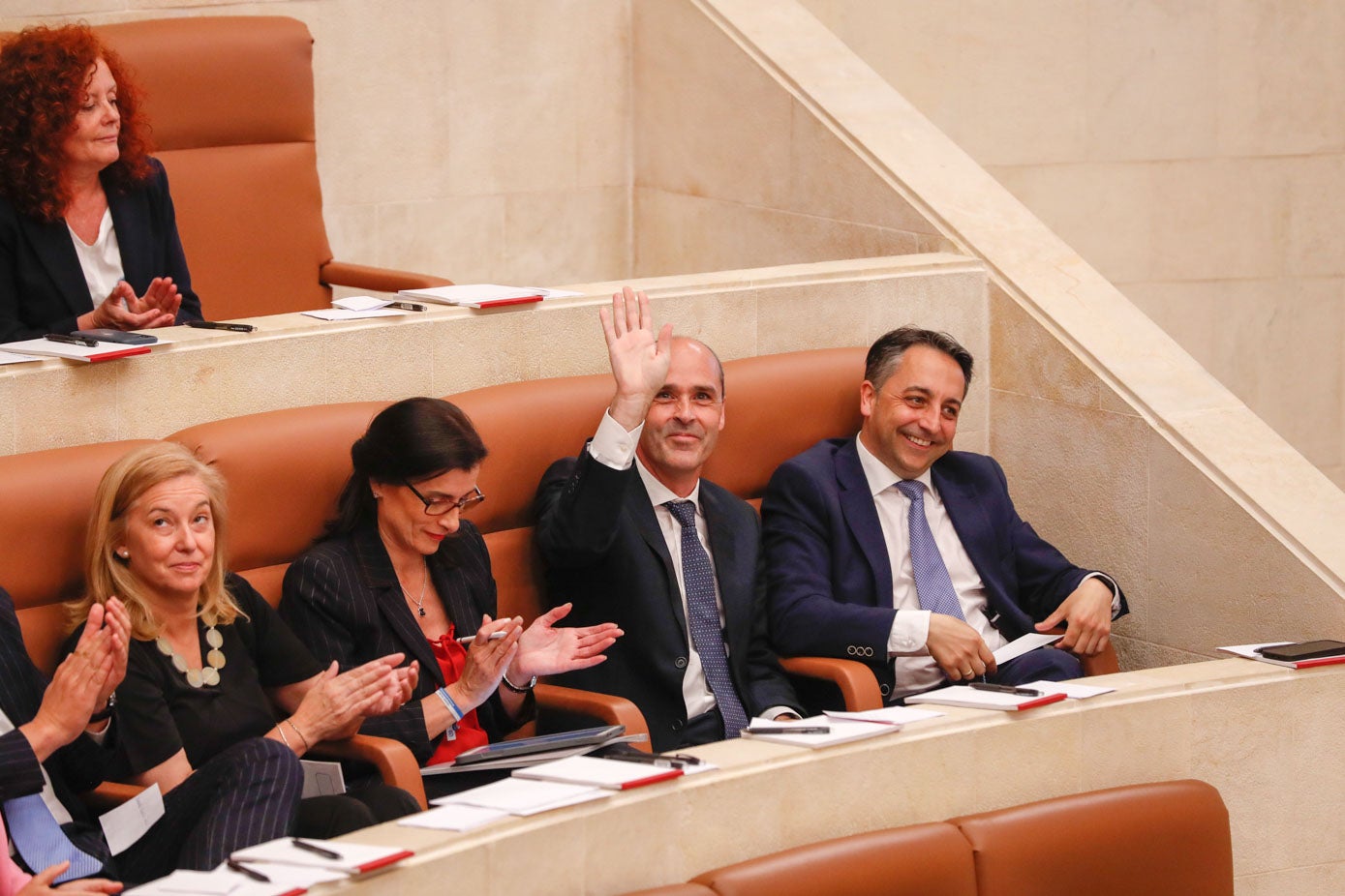 Juan José Alonso saluda tras ser elegido vicepresidente primero del Parlamento, mientras aplauden González Revuelta, Igual y Caramés sonríe.