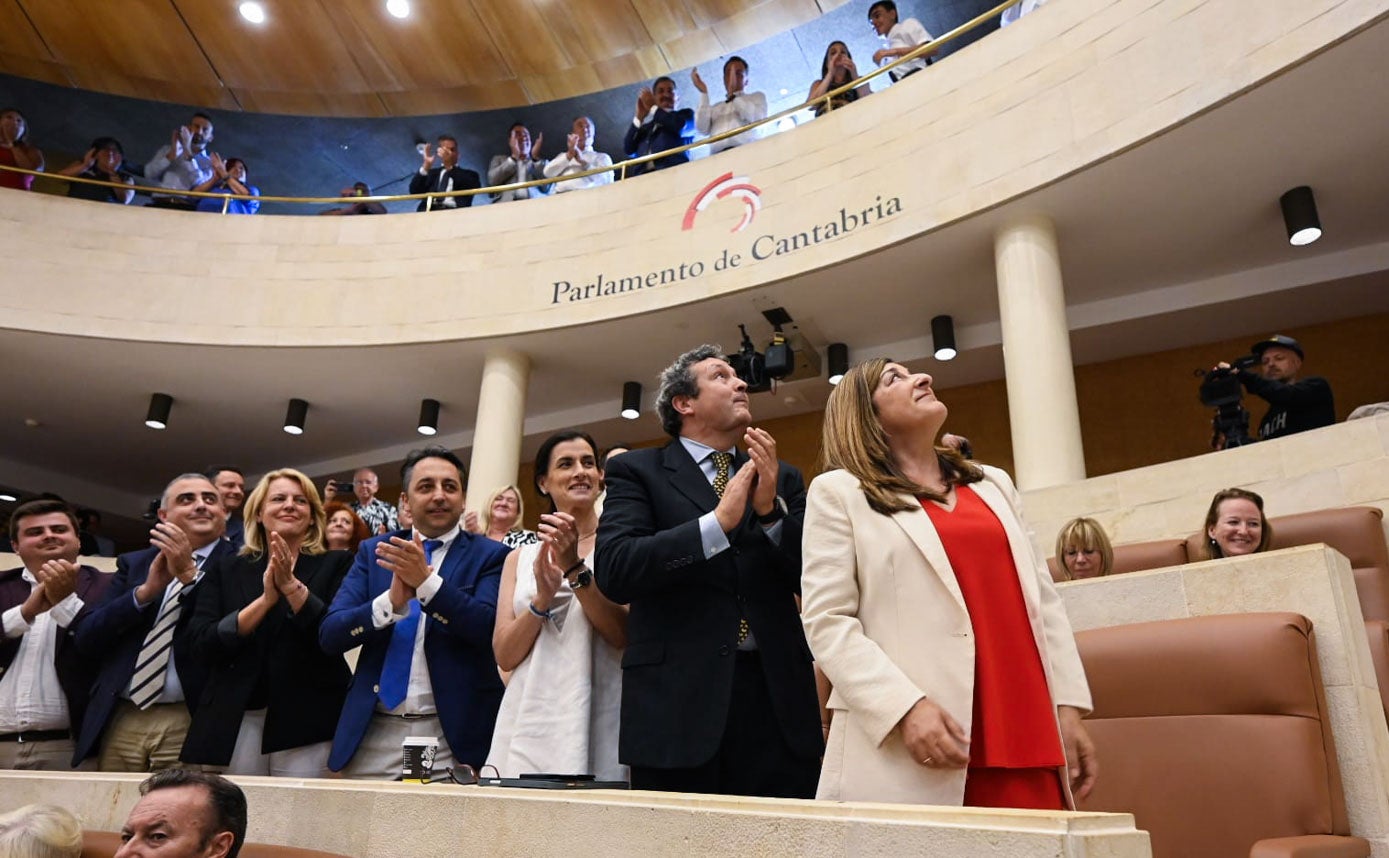 Invitados a la sesión (arriba) y otros diputados aplauden a una emocionada Buruaga. 