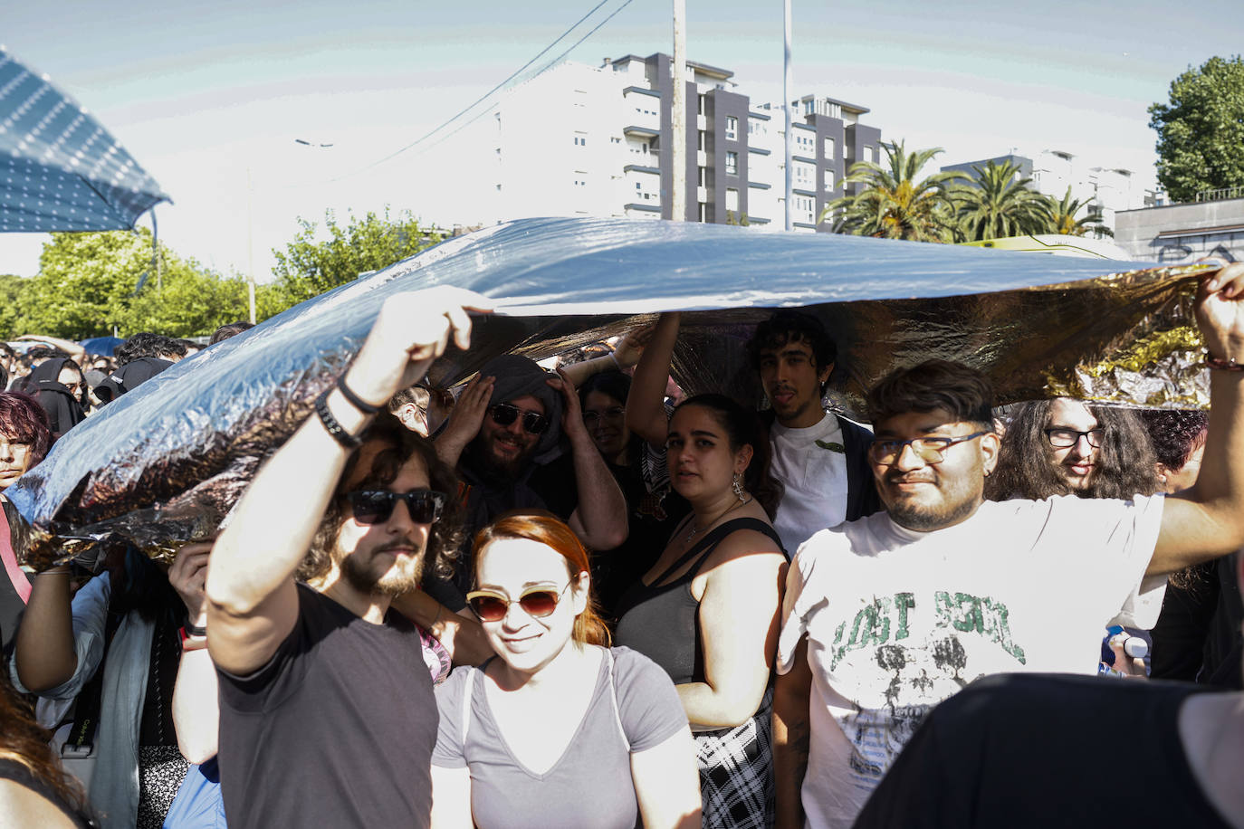 Un grupo, en la cola, se protege del sol con una lona.