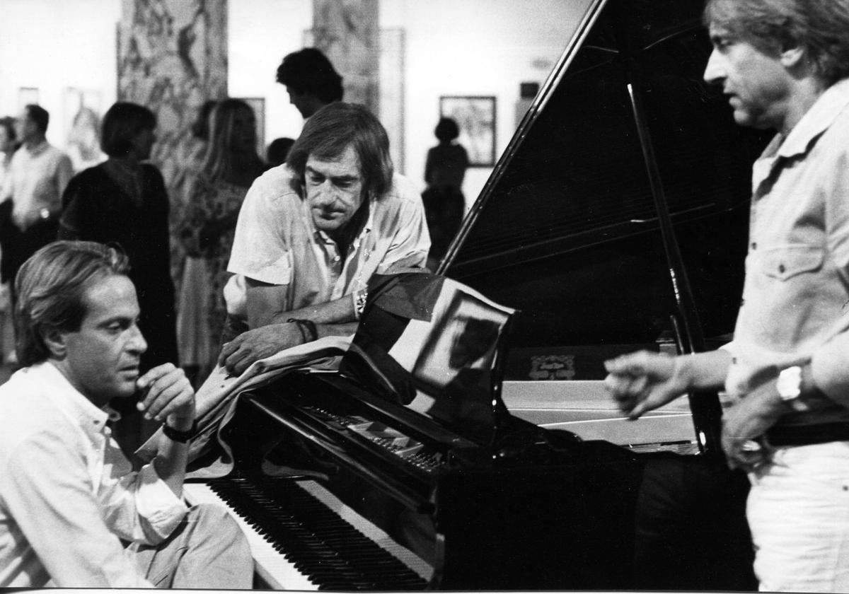 El músico Juan Carlos Calderón, junto al piano, flanqueado por sus hermanos, los artistas Fernando (d) y Ramón.