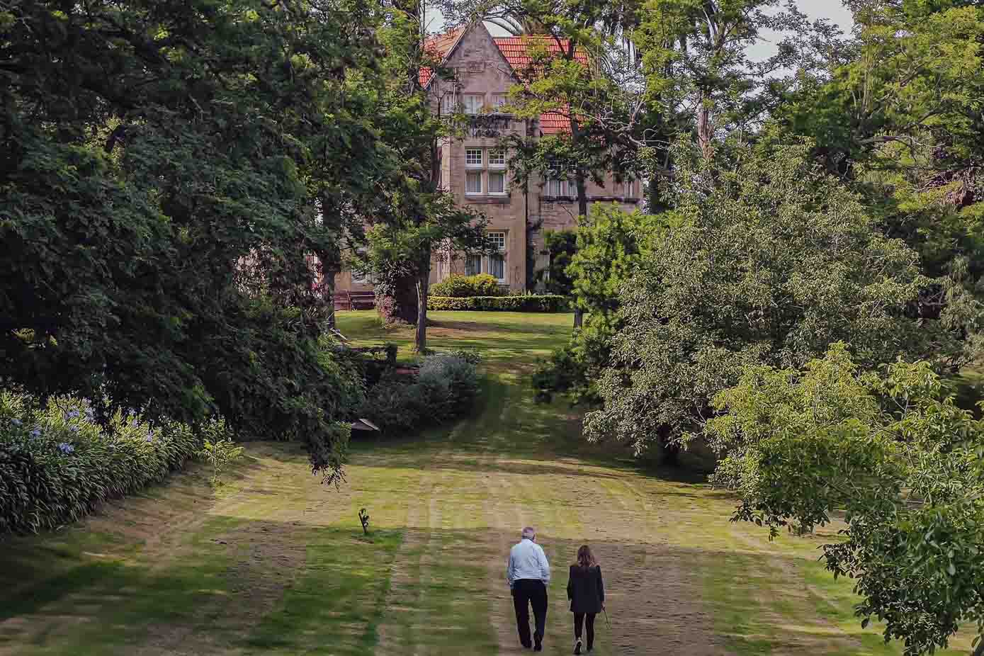 El dueño de la propiedad y la periodista, de paseo por los jardines, con la casa al fondo. 