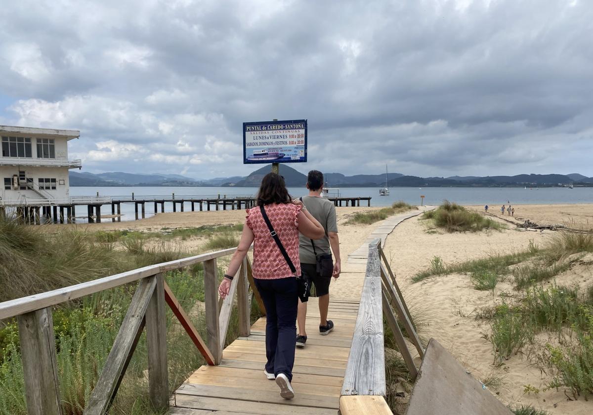 Dos personas caminan por la plataforma que conduce hasta el embarcadero del Puntal.