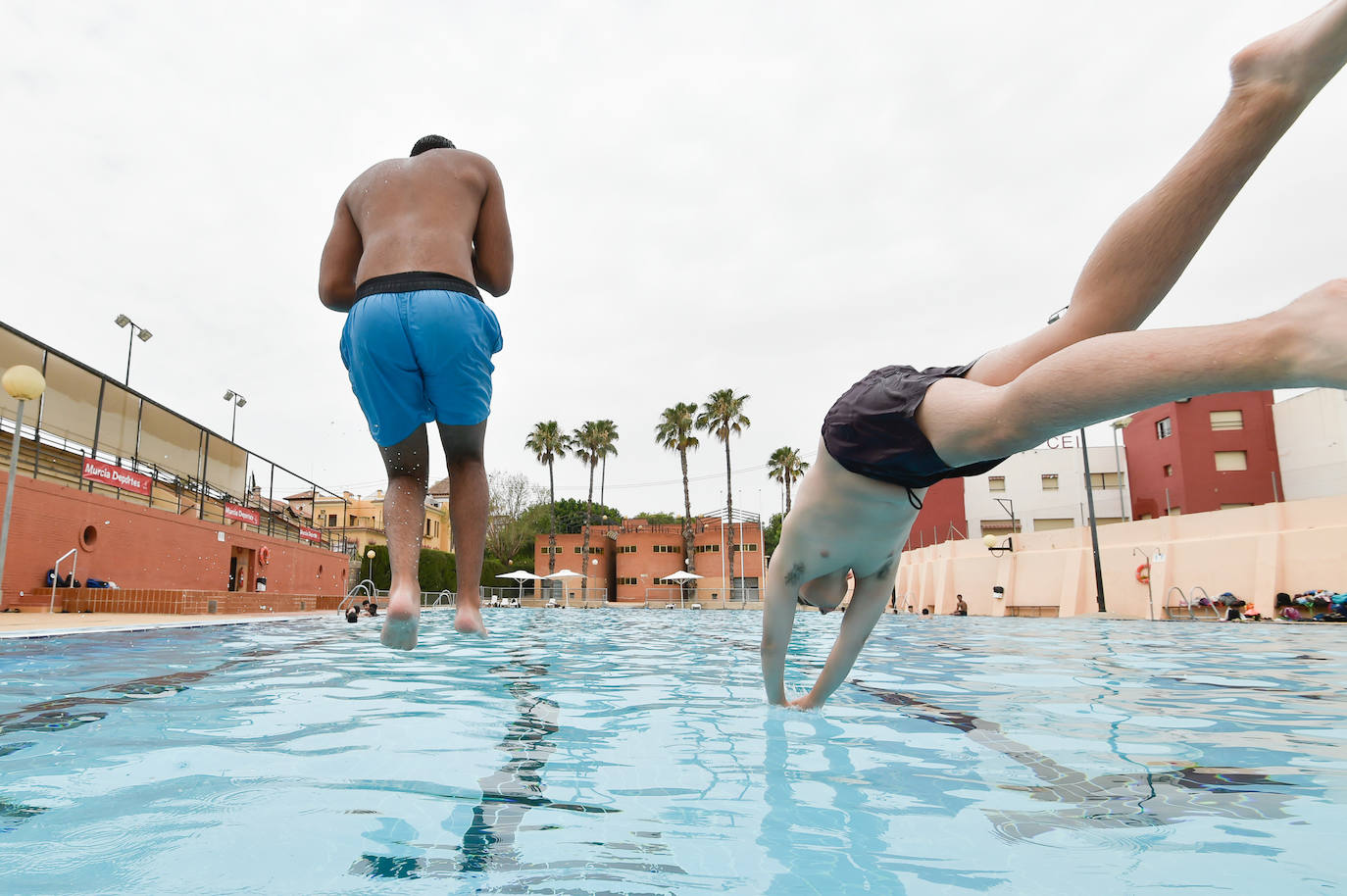 Dos jóvenes saltan a una pisicina.