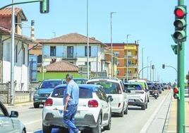 Un vecino cruza un paso de peatones, esta semana, mientras una hilera de coches se alarga por la Avenida de Solvay (Barreda).