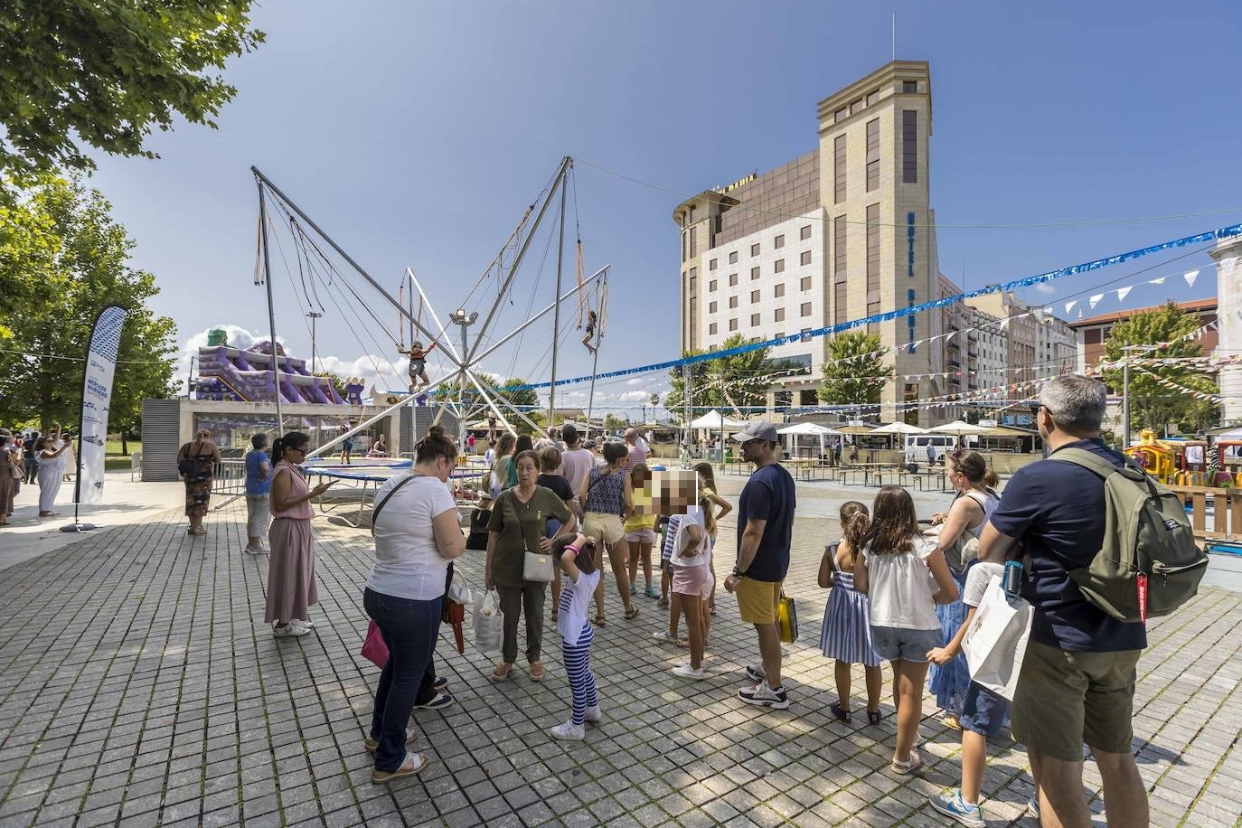 Familias y pequeños hacen cola para subirse uno de los juegos de la Plaza Alfonso XIII.