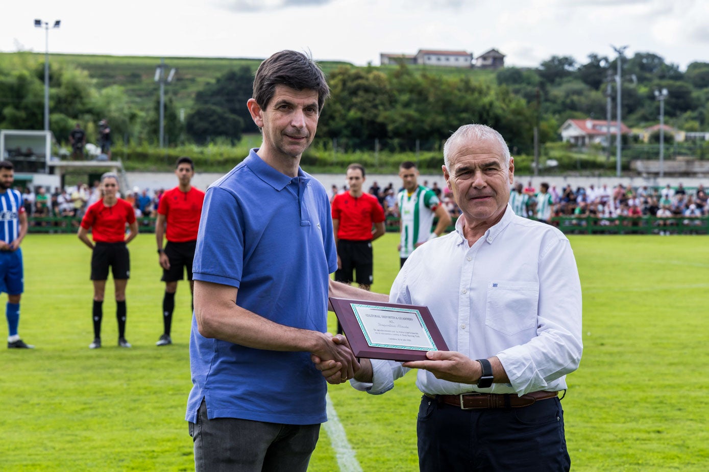 El presidente del Alavés, Alfonso Fernández de Trocóniz, recibe una placa con memorativa del encuentro de manos del presidente de la Cultural de Guarnizo, José Luis López.