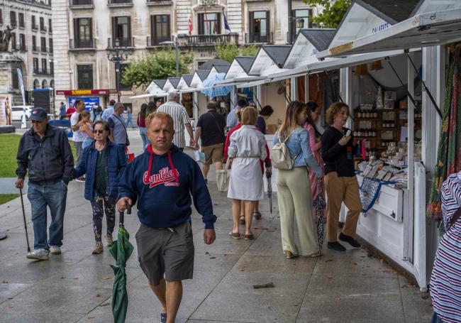 Los clientes paseando con el paraguas en la mano entre las casetas del Mercado Marinero.