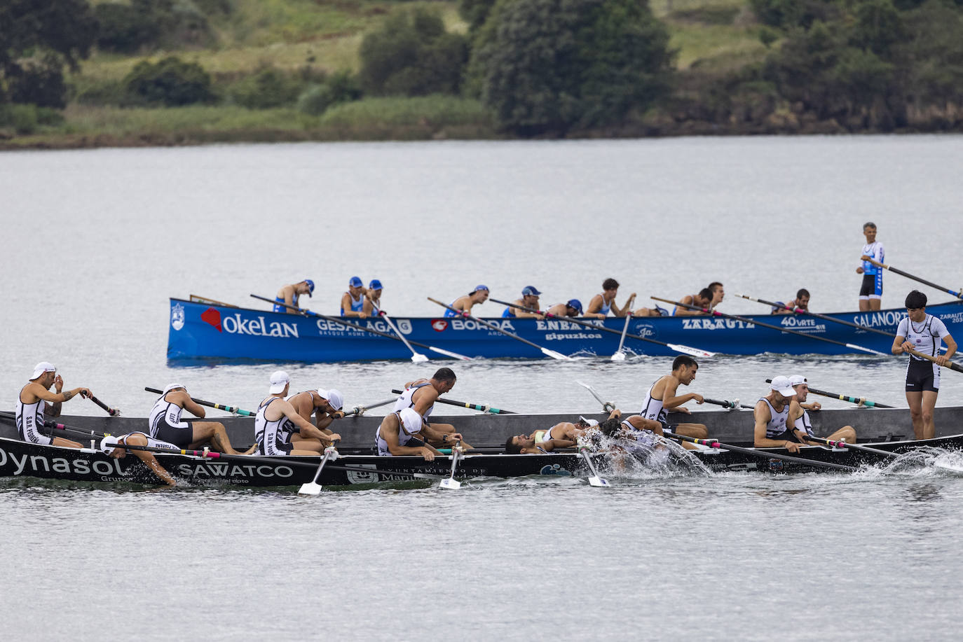 Los remeros de Pedreña, en primer término, exhaustos al terminar la regata, Al fondo Zarautz