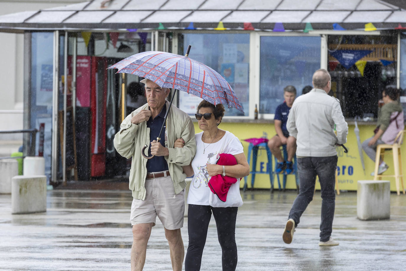 U﻿na pareja por el Paseo de Pereda da una vuelta por la ciudad y trata de resguardarse de la lluvia con el paraguas.