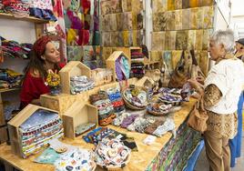 Una visitante charla con una artesana en uno de los puestos de la feria