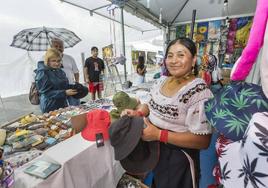 Unos visitantes, bajo el paraguas, en uno de los puestos del Festival de las Naciones.