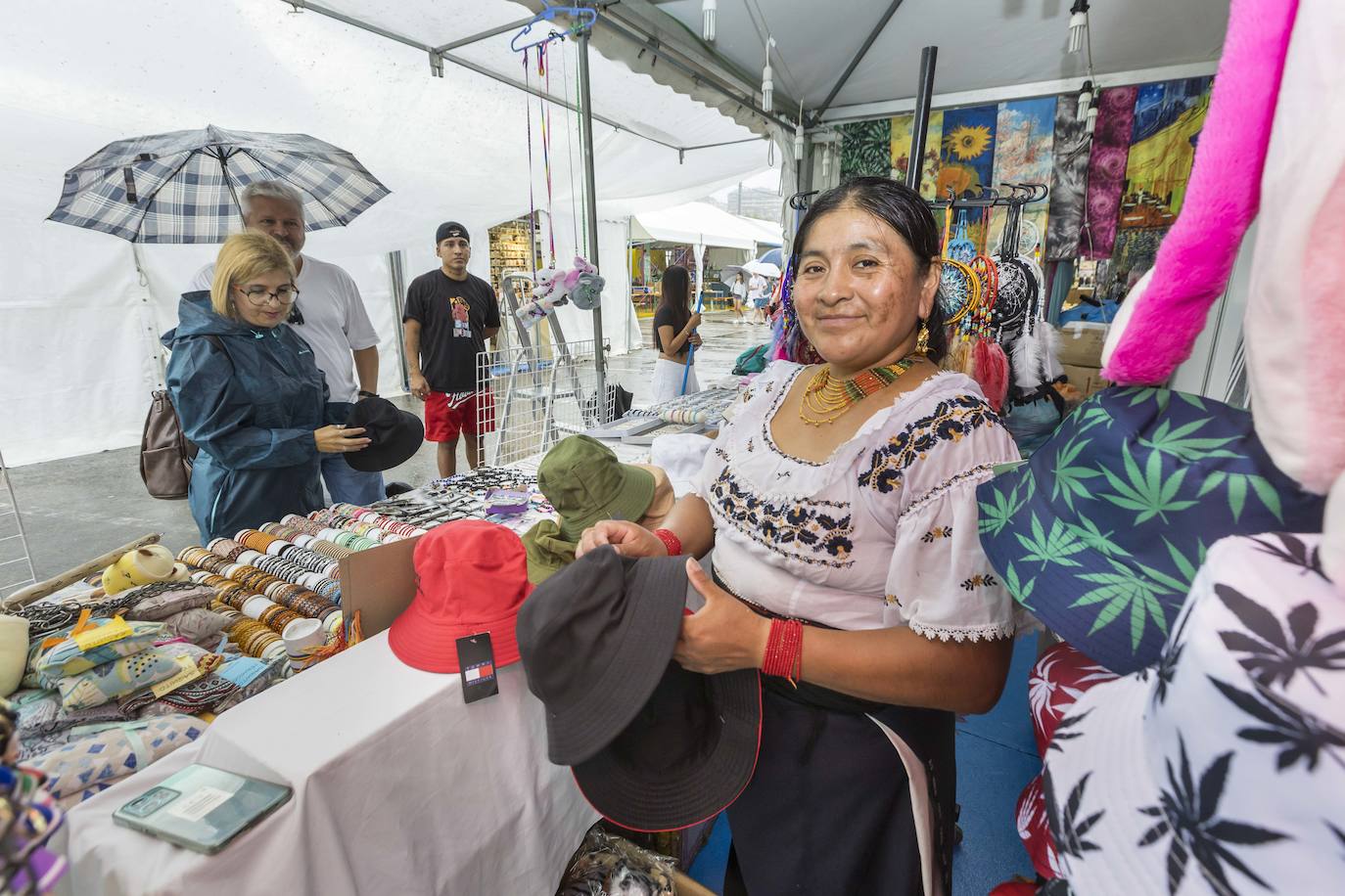 Unos turistas ojean los gorros de lluvia en uno de los puestos del Festival de las Naciones.