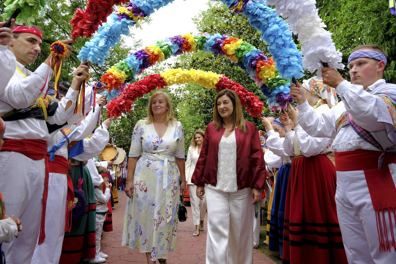 María José Gonzalez Revuelta y María José Sáenz de Buruaga bajo los arcos de flores al entrar en el parque Conde de San Diego, como marca la tradición del Día de Cantabria