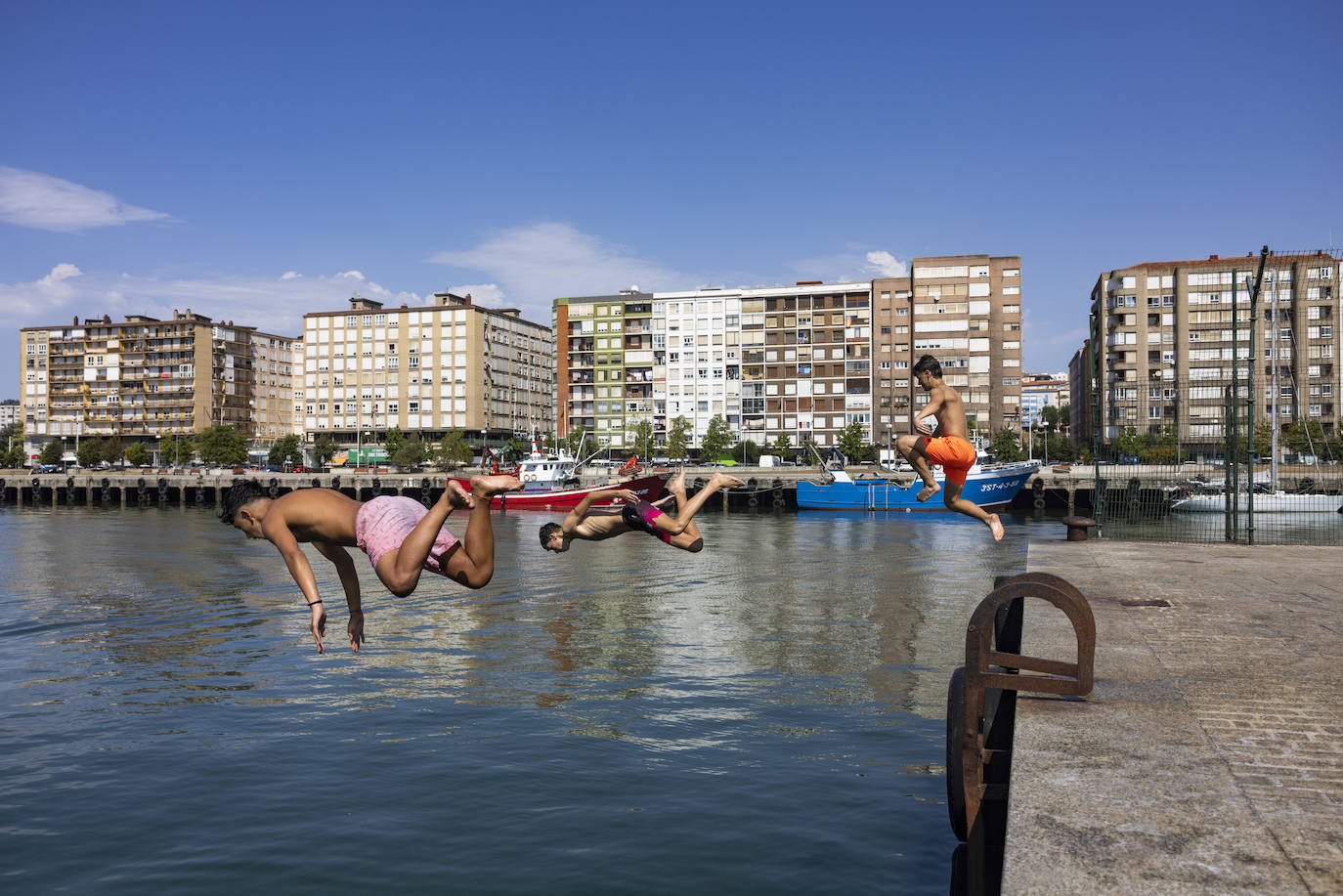 Tres jóvenes se refrescan en los muelles del Barrio Pesquero